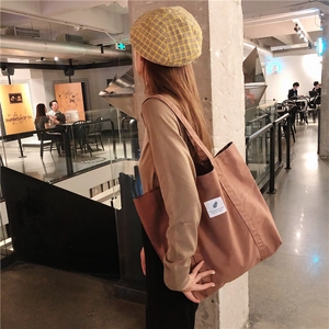 Brown canvas tote bag shoulder view showing large capacity and minimalist design