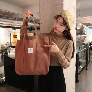 Close-up of brown corduroy tote bag featuring a white square label and wide straps