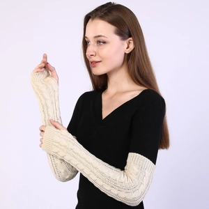 Detail of cream cable knit fingerless gloves showing thick texture and arm sleeve length