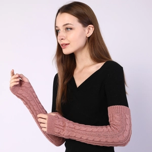 Close-up of pink cable knit arm warmers showing thick braided texture and thumb hole
