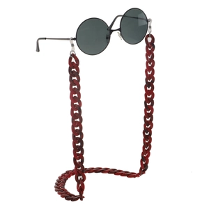 Detail of dark red acrylic leopard eyeglass chain attached to retro round sunglasses