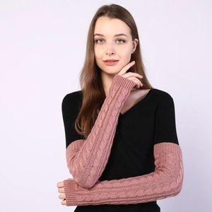 Detail of pink cable knit arm warmers showing thick braided texture and fingerless design