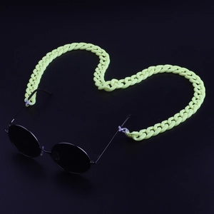 Detail of neon yellow acrylic eyeglass chain with black sunglasses on dark backdrop