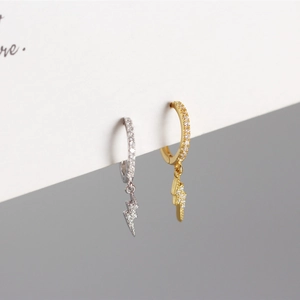 Macro shot of silver and gold lightning bolt hoop earrings with shimmering crystals