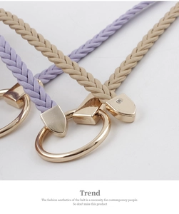 Close-up of woven leather belts in purple and beige with gold metal round buckles