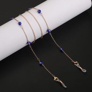 Golden chain eyewear strap with blue evil eye beads wrapped on a white cylinder stand