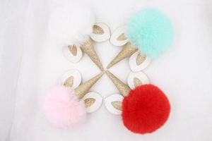 Detail of colorful plush unicorn pompom keychains in red, pink, white and mint green