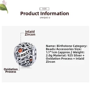 Detail of January birthstone charm in 925 silver with red zircon and floral engraving