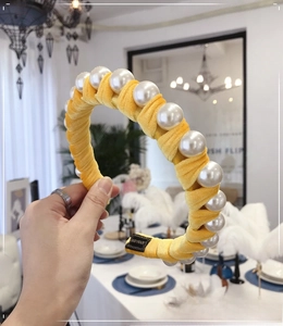 Detail of yellow velvet headband with large white pearls and handmade woven label