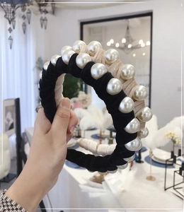 Detail showing large artificial pearls on a velvet headband with black and beige design