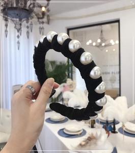 Detailed view of large white pearls hand-wrapped on a black velvet wide headband