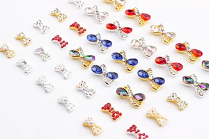 Dettagli macro di ciondoli a fiocco per nail art con strass colorati e base in metallo oro