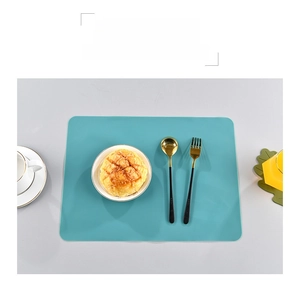 Close-up of mint green silicone placemat on a set table with coffee and utensils