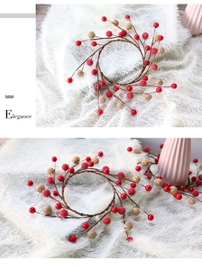 Close-up of red and gold berry Christmas wreath on white plush background with ceramic vase