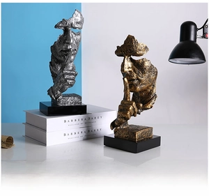Detailed close-up of gold and silver Nordic Silence is Gold resin statues on black bases
