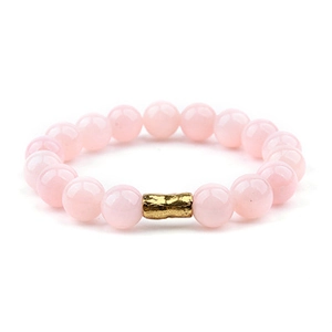 Dettaglio del bracciale con perline di cristallo rosa e tubo in metallo dorato martellato