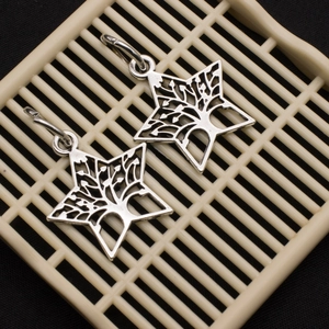 Detail of silver tree of life hexagram star earrings on a beige grid textured background