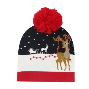 Winter knitted Christmas beanie with reindeer pattern, red pom-pom, and cozy snowflakes