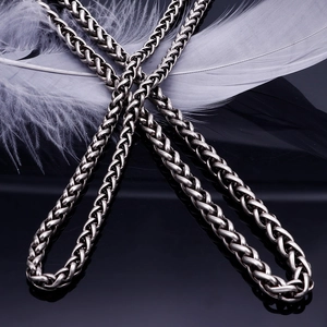 Minimalist silver titanium steel rope chain necklace on black reflective surface with feather