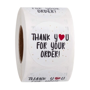 Roll of white thank you stickers with black script font and red heart for packaging decoration