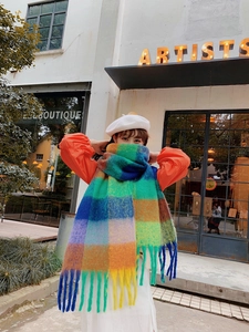 Street style shot of a thick colorful plaid scarf with fringes in a bright outdoor setting