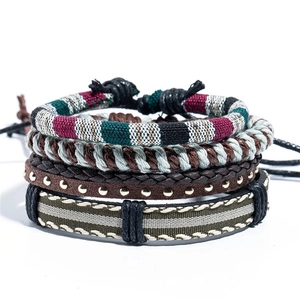Detail of four handmade ethnic bracelets featuring woven fabric, leather, and metal studs