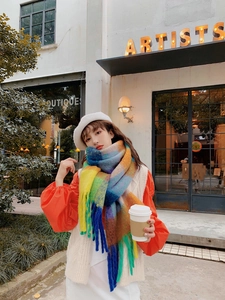 Outdoor shot of a model wearing a soft rainbow plaid scarf with long tassels and fringe