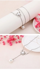 Détail d'un pendentif papillon argenté avec perles sur un collier au style minimaliste