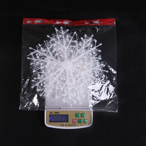Detailed view of white glitter Christmas snowflake hanging ornament on a digital scale