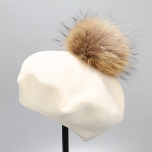 Detail of cream wool knit beret with a fluffy dark brown fur pom-pom on top