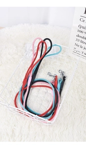 Détail de laisses pour chiens en nylon coloré avec boucles métalliques dans un panier blanc