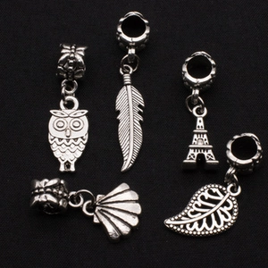 Detailed view of silver alloy pendants including owl, feather and leaf for DIY jewelry