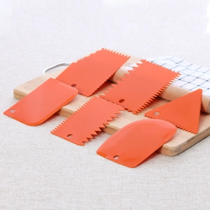 6-piece orange plastic cake scraper set with serrated edges on a wooden board