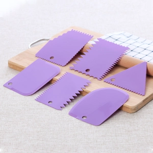 Detailed view of 6-piece purple plastic cake scrapers with various serrated edges on wood