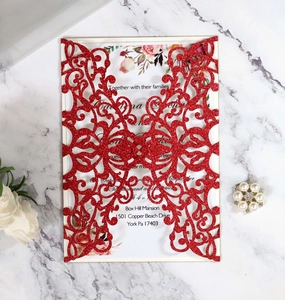 Close-up of glitter red laser-cut wedding invitation with elegant floral interior card