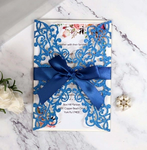 Detail of glitter blue laser cut wedding invitation with ribbon and floral insert