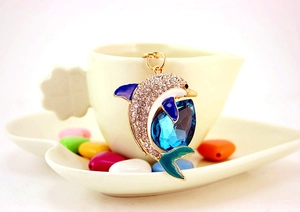 Close-up of a sparkling dolphin keychain with blue crystals in a white heart dish