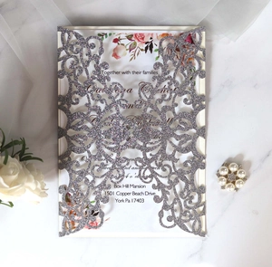 Detail of laser-cut silver glitter wedding invitation with elegant floral lace pattern