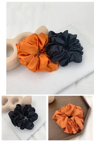 Detail of satin scrunchie set in black and orange colors with silky texture sheen