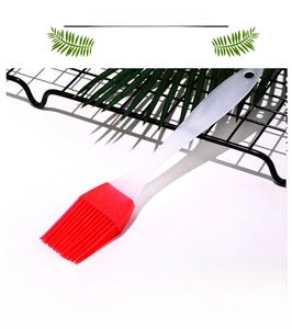 Detail of red silicone brush head with heat-resistant bristles and white plastic handle
