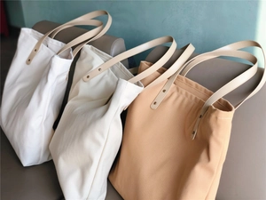 Detail of canvas tote bags with premium leather handles and metal rivet reinforcement