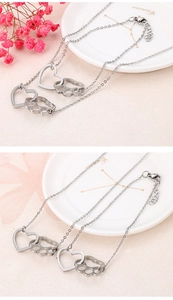 Détail du collier double couche argenté avec pendentifs ajourés en cœur et patte