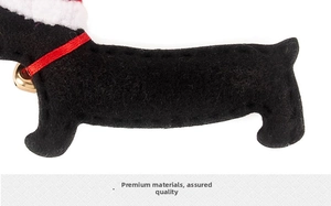 Detail of dachshund Christmas ornament with red ribbon, gold bell and felt texture