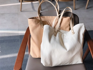 Detail of canvas tote bags showing leather handles and metal rivets on thick fabric