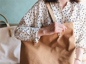 Close-up of large canvas tote bag with thick brown fabric and premium leather handles