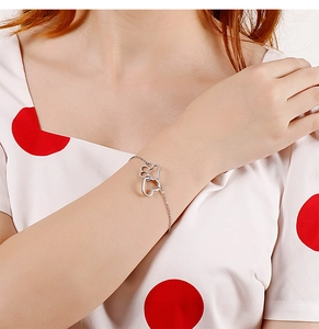 Gros plan détaillé d'un bracelet en argent avec pendentifs coeur évidé et patte de chat