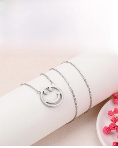 Détail du pendentif découpé en forme de sourire sur une chaîne en acier poli