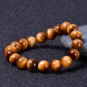 Macro detail of natural tiger eye bead bracelet with golden luster on dark stone