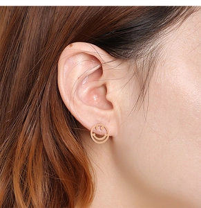 Gros plan de boucles d'oreilles en acier titane doré avec motif de visage souriant