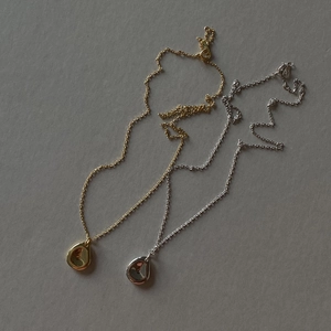 Close-up of minimalist gold and silver teardrop pendants with polished mirror finish